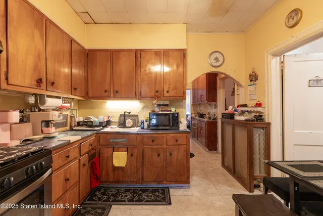 a kitchen with stainless steel appliances granite countertop a stove a sink a refrigerator and wooden cabinets