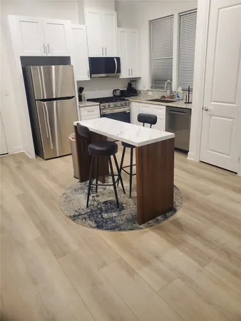 a kitchen with stainless steel appliances kitchen island granite countertop a refrigerator a stove a sink and a microwave