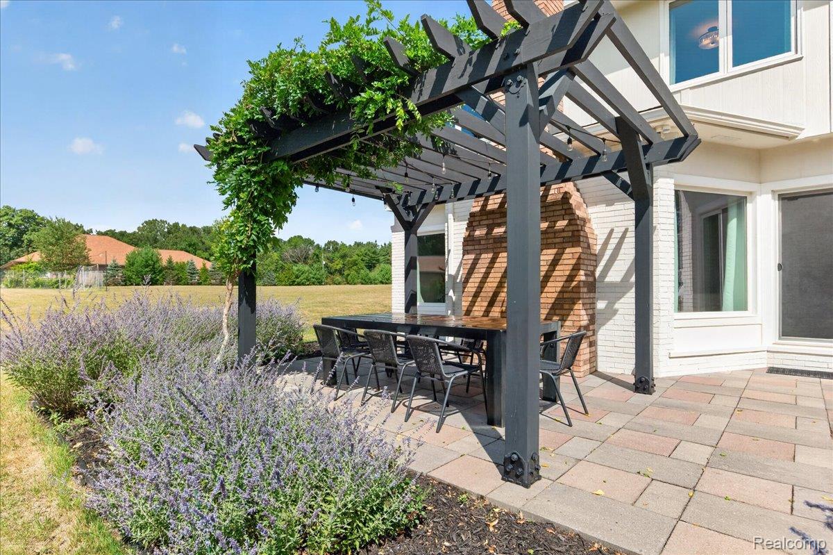 7330 West Gates Street Romeo, MI 48065 - Photo 52 of 73 Paved patio with a dark pergola featuring established climbing greenery, brick exterior, and a manicured lawn beyond