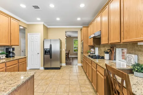 a large kitchen with stainless steel appliances granite countertop a refrigerator a sink a stove and oven