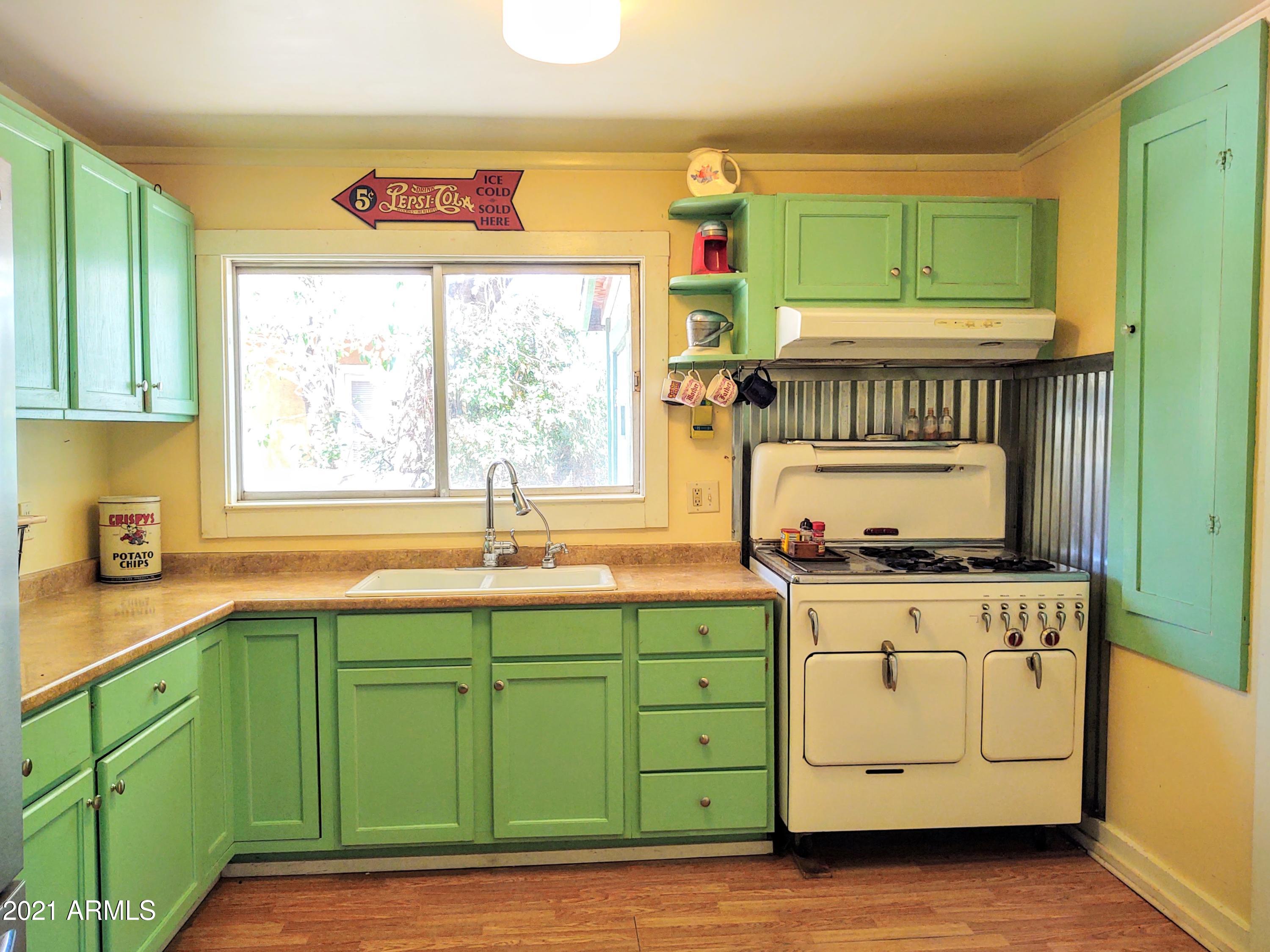 32 Old Douglas Road Bisbee, AZ 85603 - Photo 4 of 16 a kitchen with a sink wooden cabinets and a large window