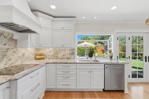 a kitchen with granite countertop white cabinets and a window