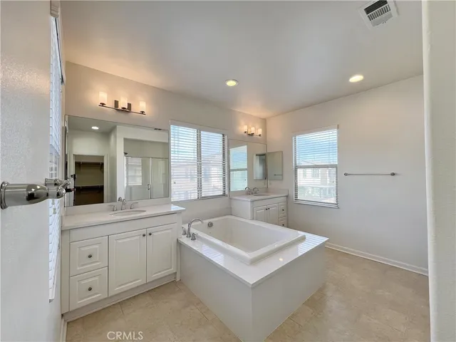 a large white kitchen with a sink a window and stainless steel appliances