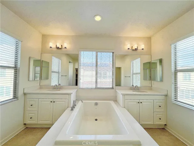 a spacious bathroom with a double vanity sink a large mirror and a bathtub