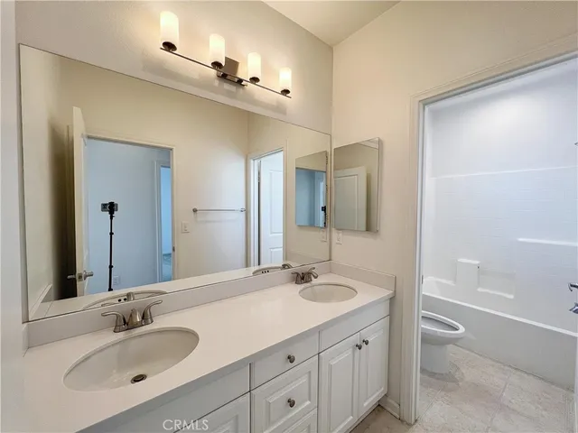 a bathroom with a sink double vanity granite tub and a mirror