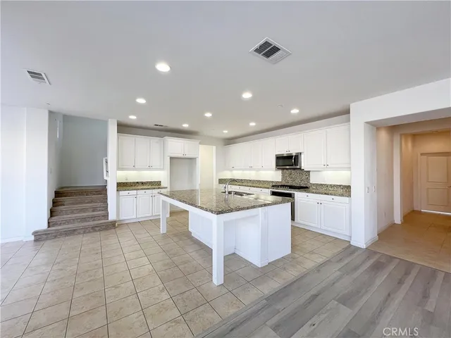 a kitchen with stainless steel appliances kitchen island granite countertop a refrigerator and a stove top oven