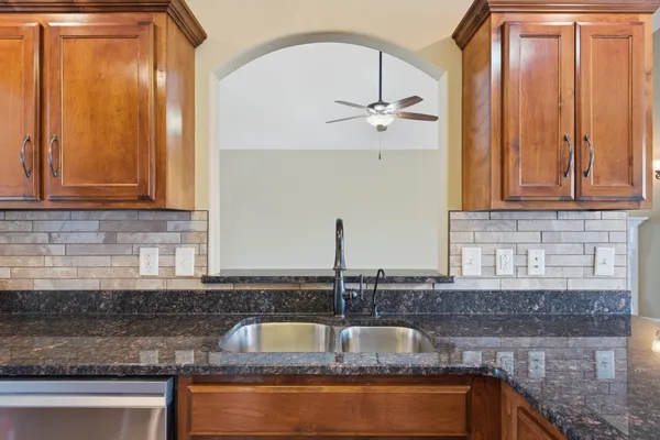 a kitchen with granite countertop a sink stainless steel appliances wooden floor and a counter top space