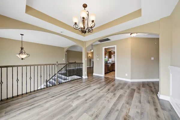 a view of a hallway with wooden floor and a chandelier