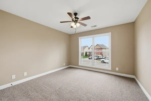 an empty room with windows and ceiling fan