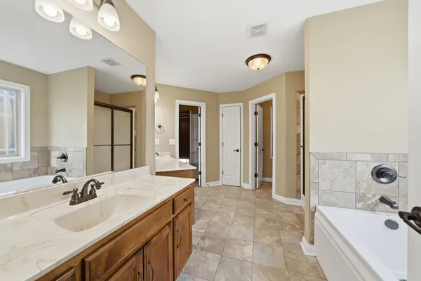 a spacious bathroom with a tub sink and mirror