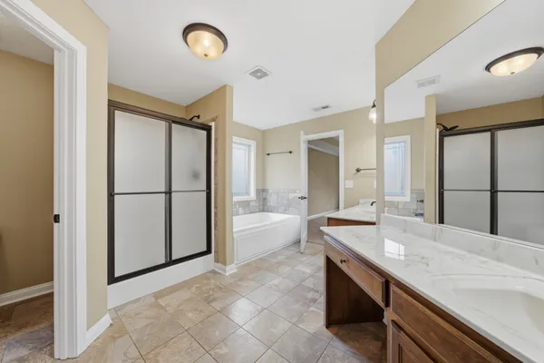a spacious bathroom with a granite countertop sink a mirror and a bathtub