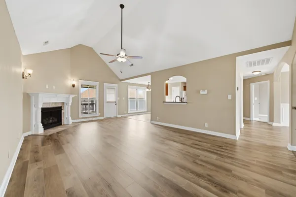 a view of an empty room with window and wooden floor