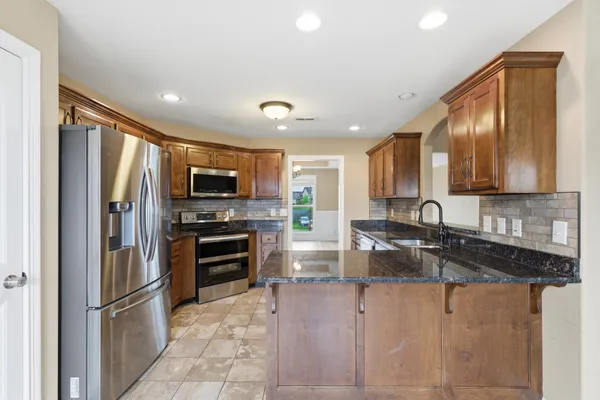 a kitchen with stainless steel appliances granite countertop a refrigerator and a stove top oven