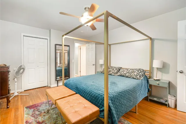 a bedroom with a bed and dresser with wooden floor