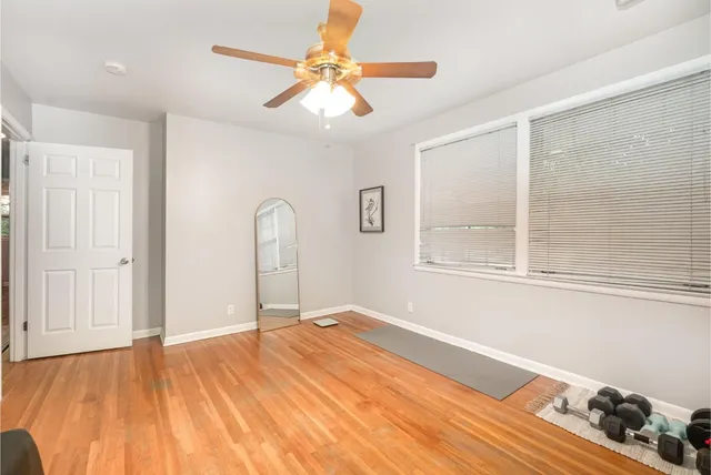 a view of empty room with wooden floor and fan