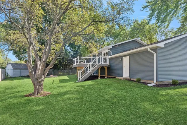 a view of a house with a yard and a large tree
