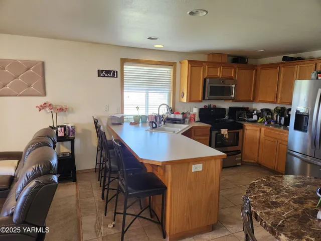 a kitchen with stainless steel appliances granite countertop a sink a stove a refrigerator cabinets and dining table