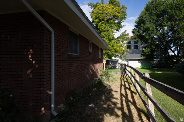 827 South 600 East Logan, UT 84321 - Photo 5 of 30 Brick exterior with white downspouts and fascia, featuring a wood rail fence bordering a grass lawn
