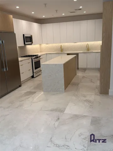 a kitchen with stainless steel appliances granite countertop a refrigerator and a stove