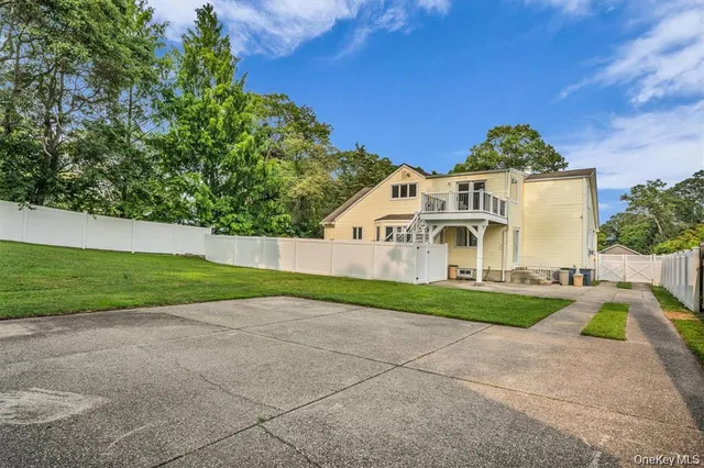 a view of a white house with a yard and large trees