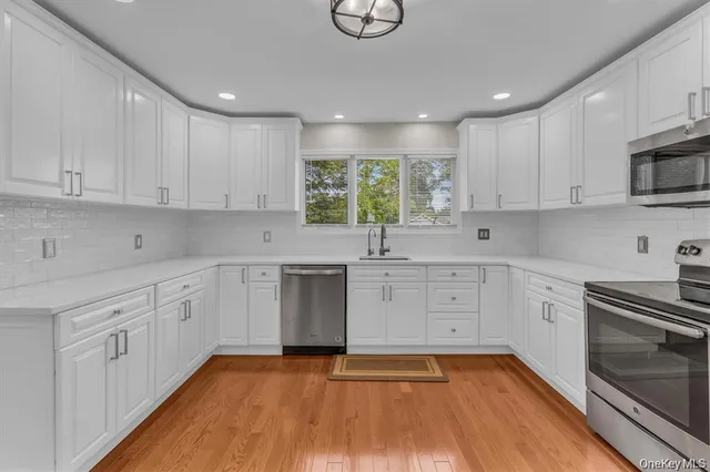 a kitchen with cabinets stainless steel appliances a sink and wooden floor