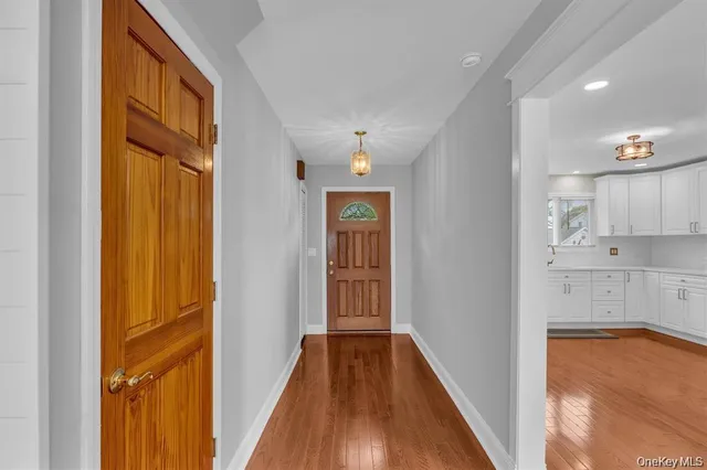 a view of a hallway with wooden floor and cabinet