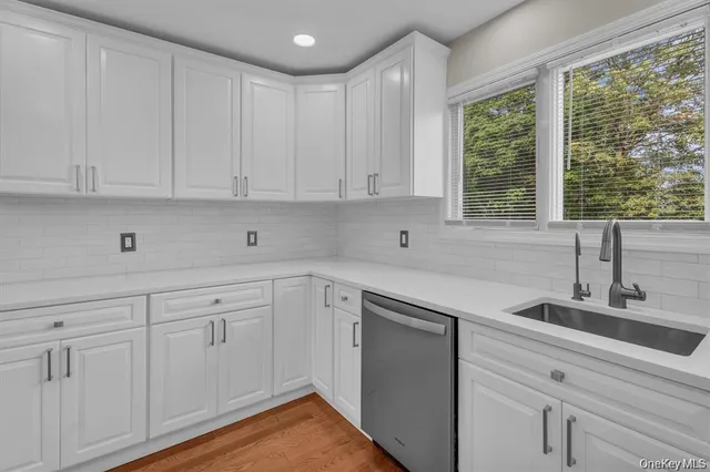 a kitchen with white cabinets and a window
