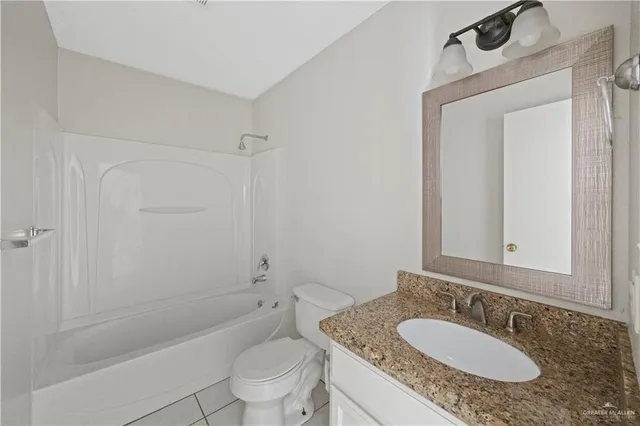 a bathroom with a granite countertop sink a toilet a mirror and shower