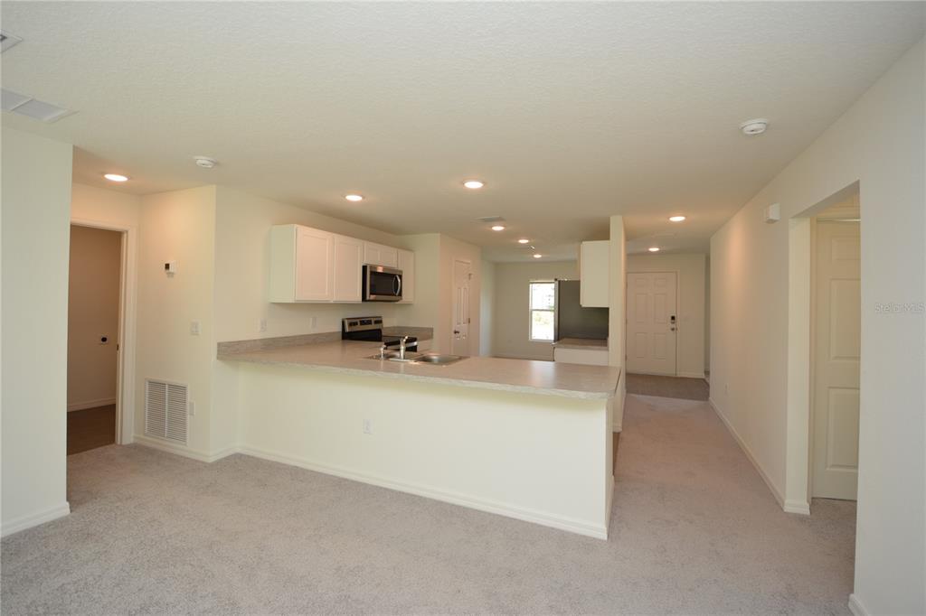 8 Sea Flower Path Palm Coast, FL 32164 - Photo 5 of 30 a view of a kitchen with kitchen island a sink wooden floor and a refrigerator