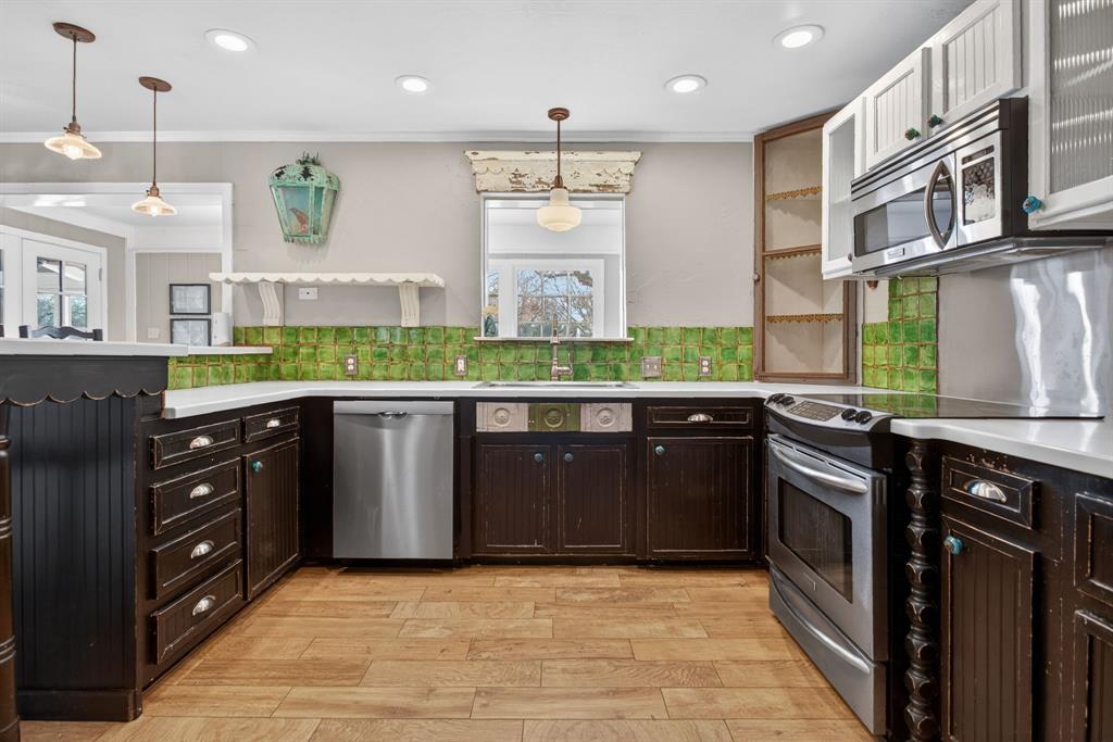 7117 Serrano Drive Benbrook, TX 76126 - Photo 11 of 26 Dual tone kitchen with stainless steel appliances, open shelves, light wood-style flooring, pendant lighting, and tasteful backsplash