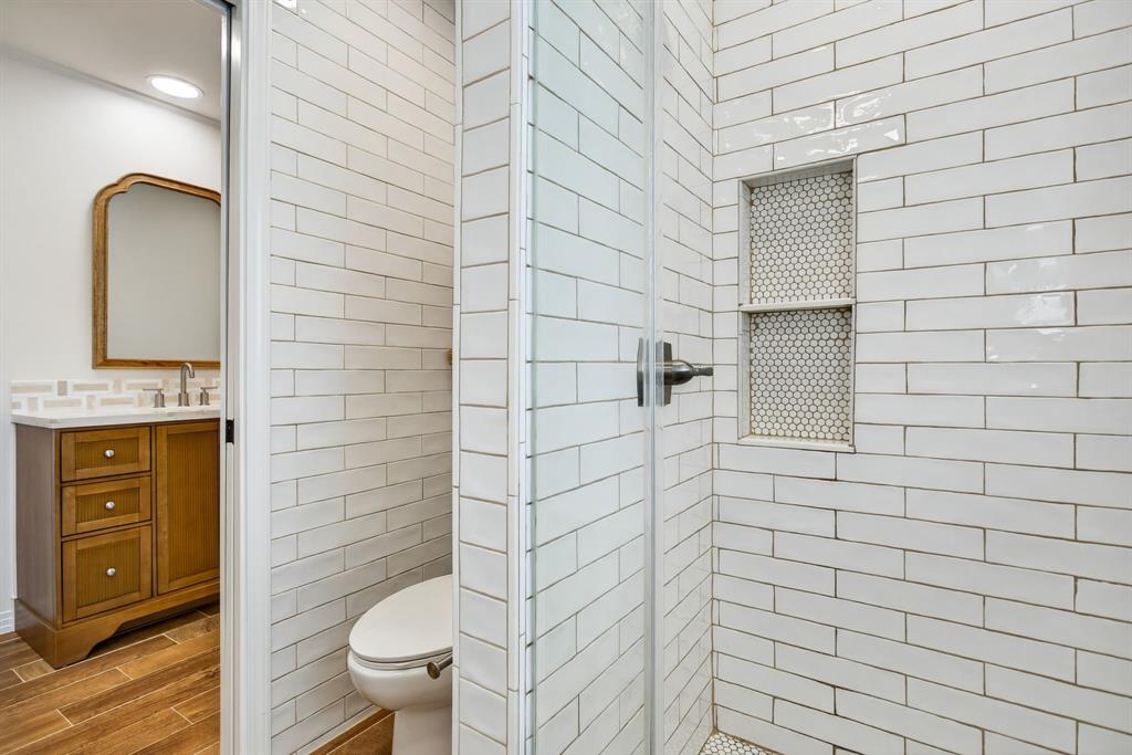 7117 Serrano Drive Benbrook, TX 76126 - Photo 20 of 26 Bathroom featuring tile walls, a shower stall, vanity, and wood tiled floors