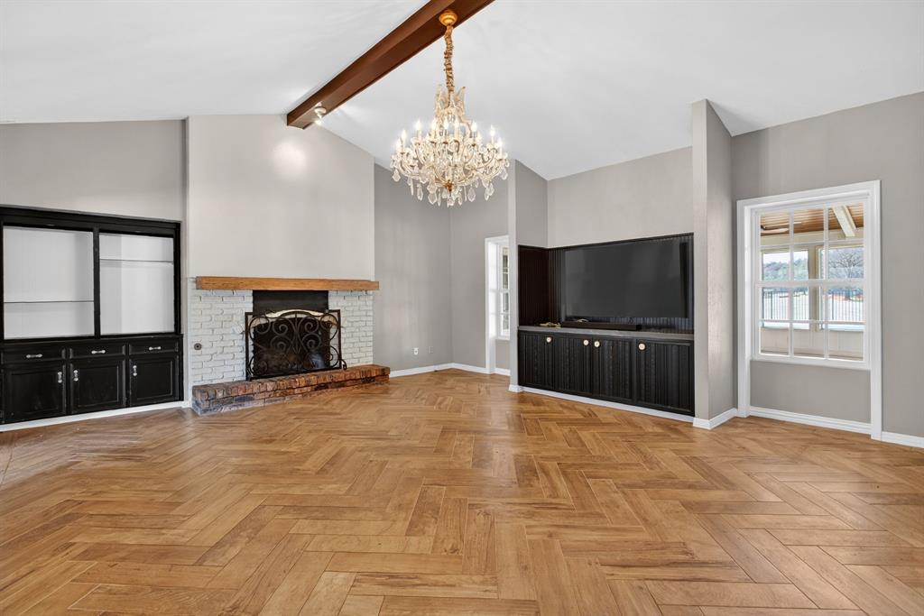 7117 Serrano Drive Benbrook, TX 76126 - Photo 7 of 26 Unfurnished living room with parquet floors, a chandelier, beam ceiling, and a brick fireplace