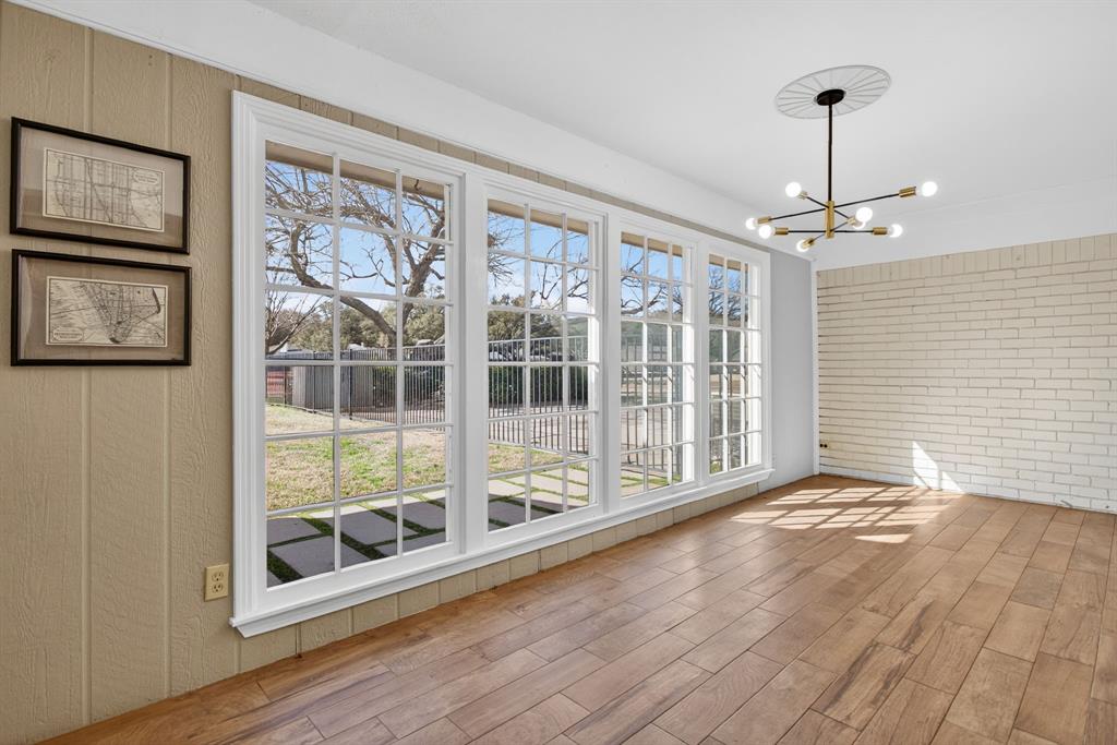 7117 Serrano Drive Benbrook, TX 76126 - Photo 9 of 26 Unfurnished dining area with brick wall, a chandelier, and wood finished floors