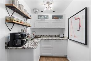 7117 Serrano Drive Benbrook, TX 76126 - Photo 10 of 26 Bar area featuring white cabinets, glass insert cabinets, light wood-style floors, and open shelves