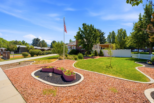 1925 South Main Street Bountiful, UT 84010 - Photo 4 of 48 Landscaped front yard featuring a manicured lawn, decorative rock beds, a flag pole, and mature trees