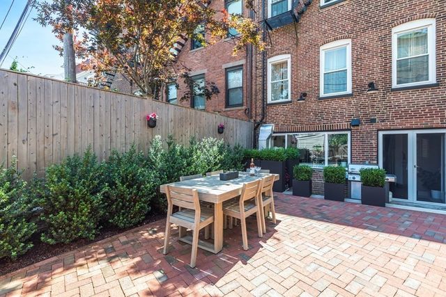 a patio with table and chairs and potted plants