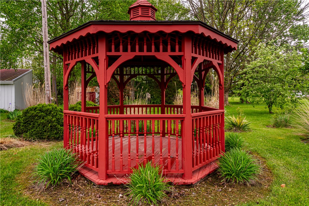11296 Pansing Road Brookville, OH 45309 - Photo 34 of 53 This charming red gazebo offers a picturesque retreat within a lush green landscape.