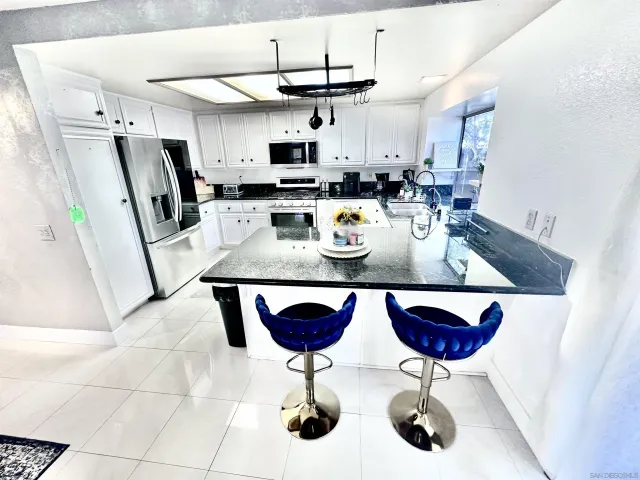 a kitchen with stainless steel appliances granite countertop a sink a stove a refrigerator a counter space and dining table