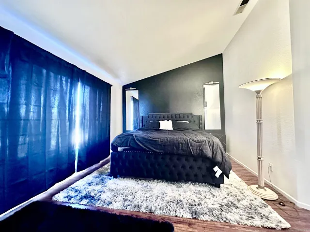 a bedroom with a large bed and wooden floor