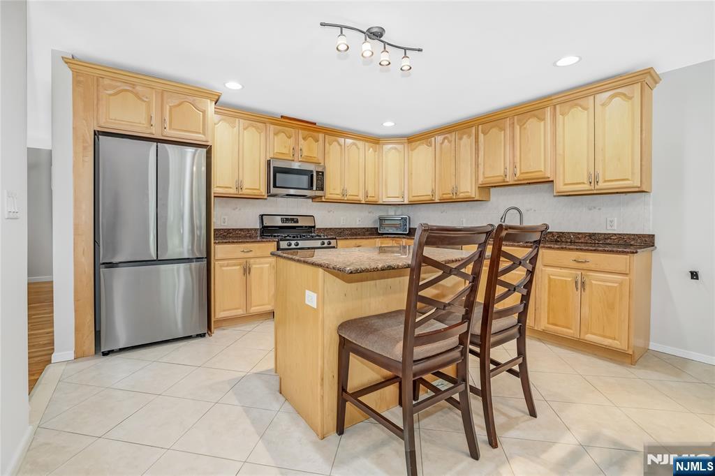 4 Maple Avenue Waldwick, NJ 07463 - Photo 11 of 34 a kitchen with stainless steel appliances granite countertop a stove a refrigerator a sink a dining table and chairs with wooden floor
