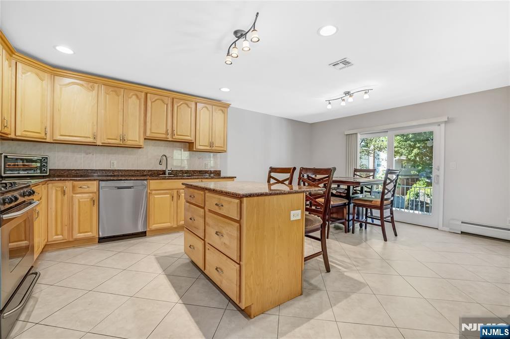 4 Maple Avenue Waldwick, NJ 07463 - Photo 10 of 34 a kitchen with stainless steel appliances granite countertop a stove top oven a sink dishwasher a dining table and chairs with white cabinets