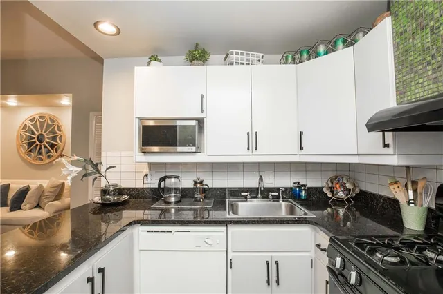a kitchen with granite countertop a sink a stove and cabinets