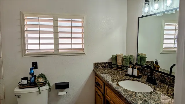 a bathroom with a granite countertop sink a mirror and a toilet