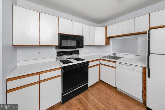 a kitchen with cabinets stainless steel appliances and wooden floor