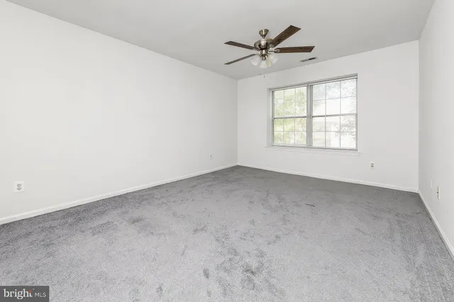 an empty room with windows and fan