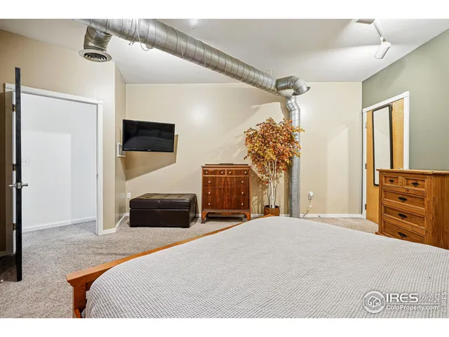 a bedroom with a bed and a flat tv screen on dresser