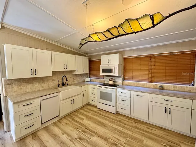 a kitchen with white cabinets and sink