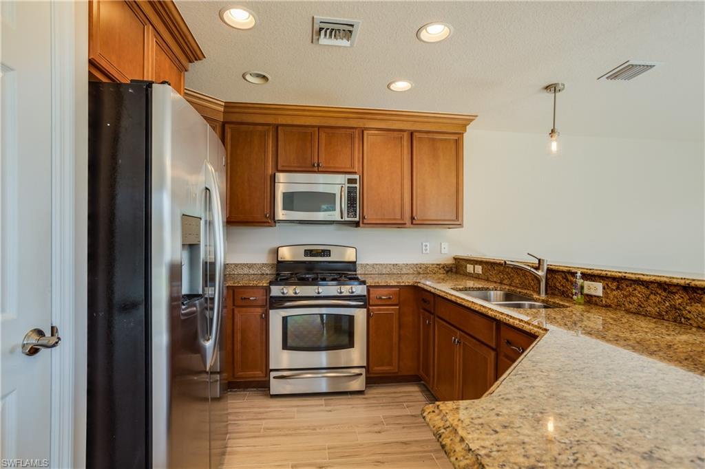 9026 Astonia Way Estero, FL 33967 - Photo 13 of 38 a kitchen with stainless steel appliances granite countertop a stove a sink and a refrigerator