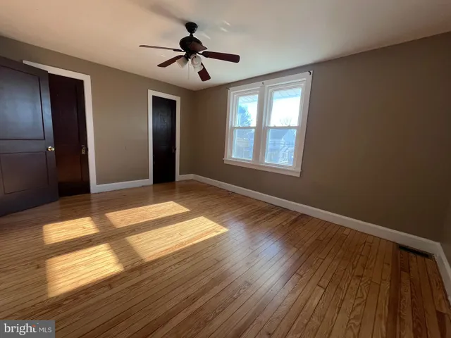 a view of empty room with wooden floor and fan