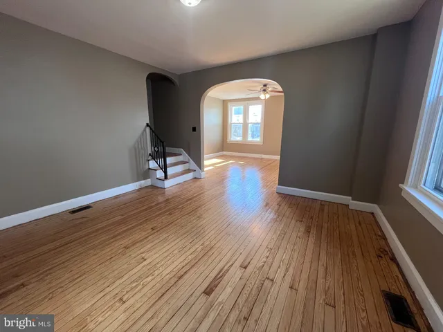 a view of empty room with wooden floor and fan